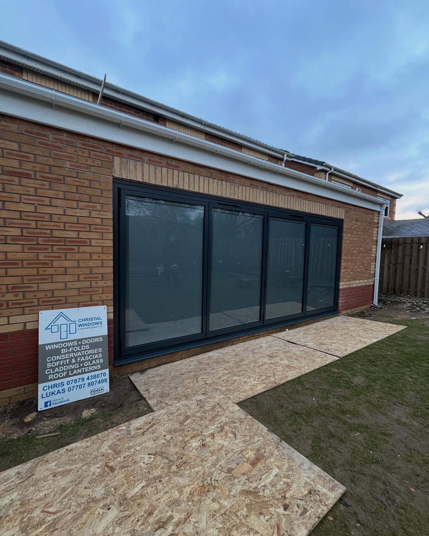 Long run of grey aluminium bifold doors and windows on a single storey extension